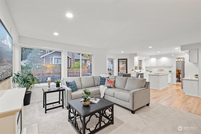 living room featuring sink, a chandelier, and light hardwood / wood-style floors