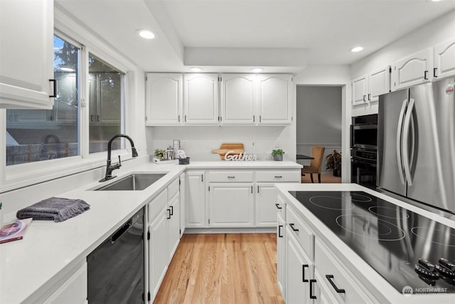 kitchen featuring white cabinetry, sink, light hardwood / wood-style flooring, and black appliances