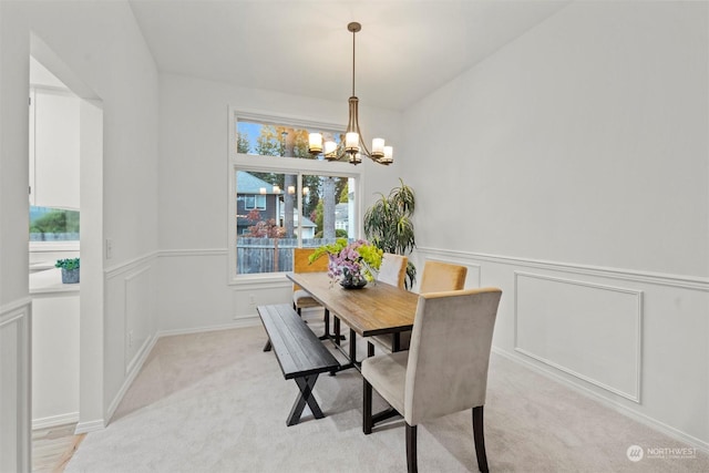 dining area with an inviting chandelier and light colored carpet