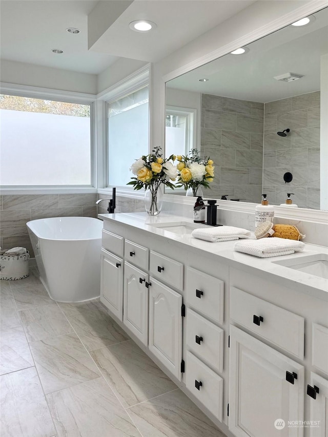 bathroom with vanity, independent shower and bath, and tile walls