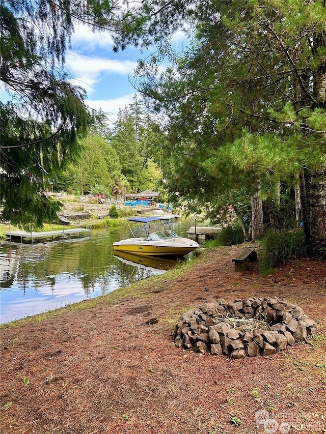 view of community featuring a water view and an outdoor fire pit