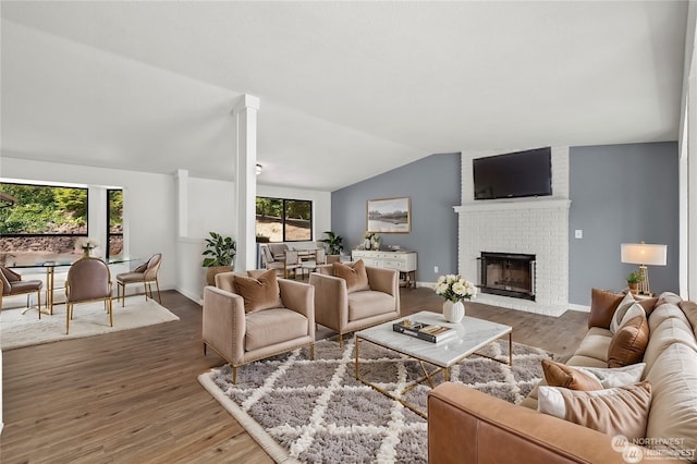 living room featuring lofted ceiling, a fireplace, a wealth of natural light, and wood-type flooring