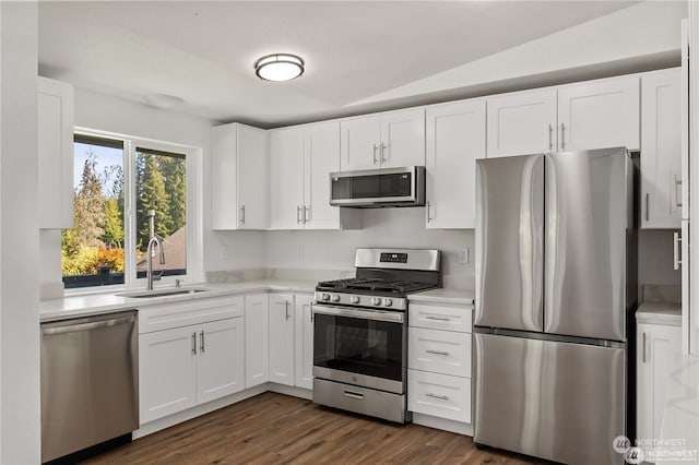 kitchen featuring dark hardwood / wood-style floors, lofted ceiling, sink, white cabinets, and stainless steel appliances