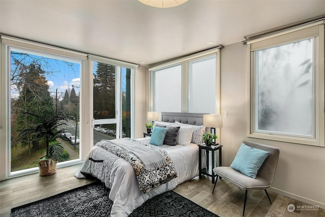 bedroom featuring multiple windows, a wall of windows, and light hardwood / wood-style floors