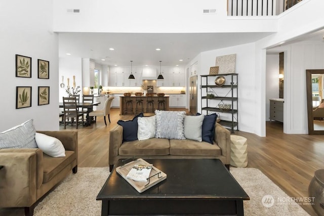 living room with a high ceiling and light hardwood / wood-style flooring