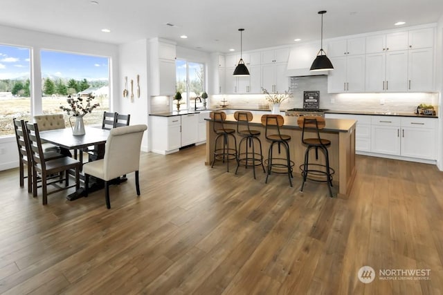 kitchen with dark hardwood / wood-style floors, white dishwasher, white cabinets, a kitchen island, and decorative light fixtures