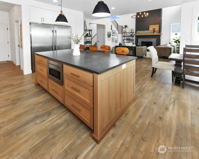 kitchen featuring pendant lighting, light hardwood / wood-style flooring, white cabinetry, a center island, and built in appliances