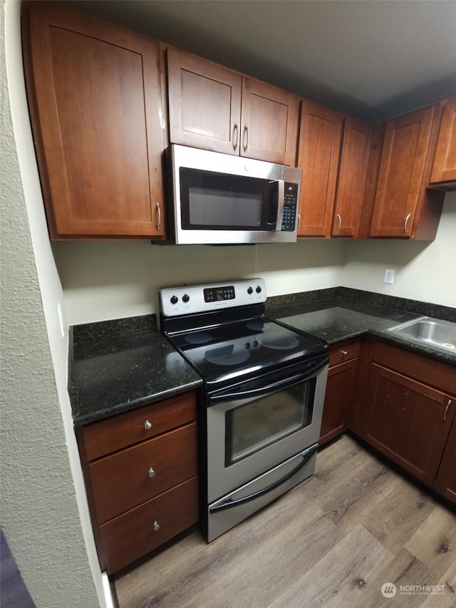 kitchen featuring stainless steel appliances, sink, and light wood-type flooring