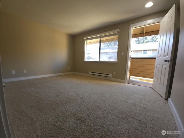 carpeted spare room with a baseboard heating unit