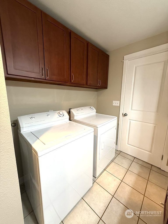 washroom with cabinets, washing machine and dryer, and light tile patterned floors