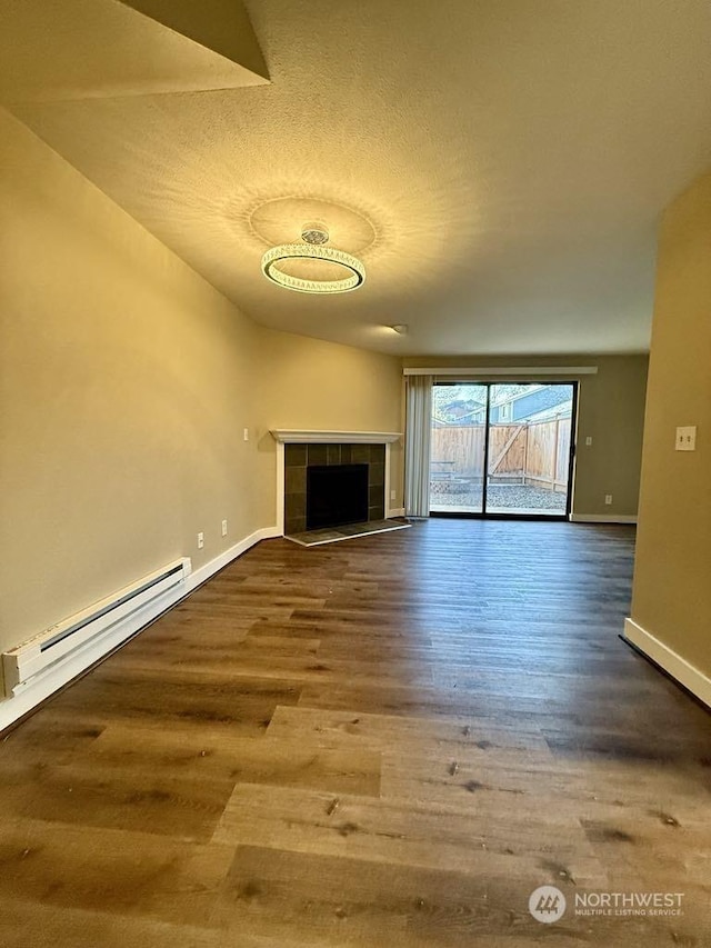 unfurnished living room featuring hardwood / wood-style flooring, a baseboard radiator, a textured ceiling, and a tile fireplace