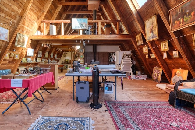 interior space with high vaulted ceiling, beamed ceiling, and a wood stove