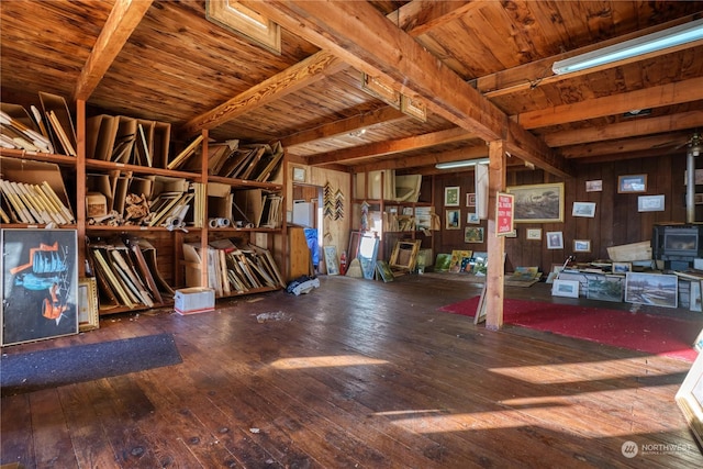 miscellaneous room featuring wooden walls, beamed ceiling, and a wood stove