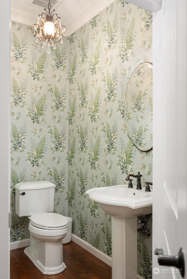 bathroom with wood-type flooring, a chandelier, and toilet