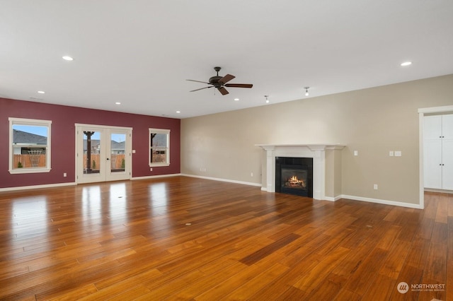 unfurnished living room with ceiling fan, a fireplace, and light wood-type flooring