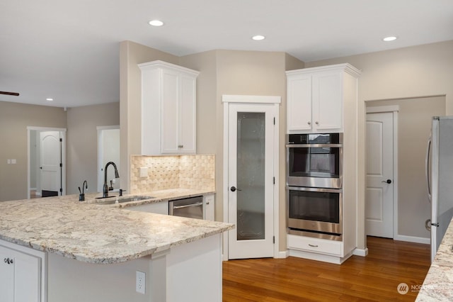 kitchen with stainless steel appliances, white cabinetry, wood-type flooring, and kitchen peninsula