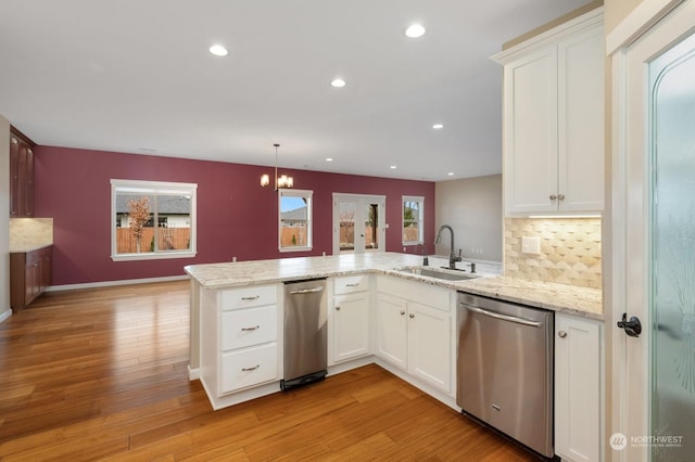 kitchen with pendant lighting, white cabinetry, dishwasher, sink, and kitchen peninsula