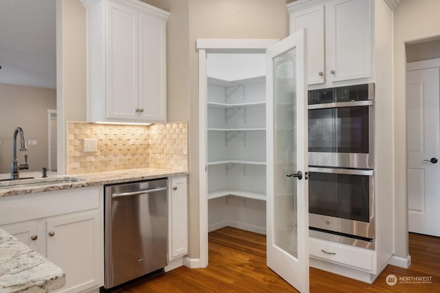 kitchen with white cabinetry, appliances with stainless steel finishes, light stone countertops, and sink