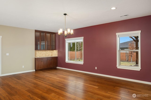 unfurnished dining area featuring dark wood-type flooring and a chandelier