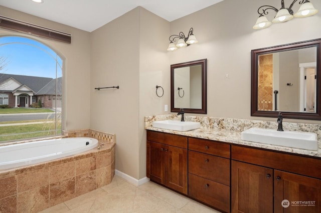 bathroom with tile patterned flooring, vanity, and tiled bath