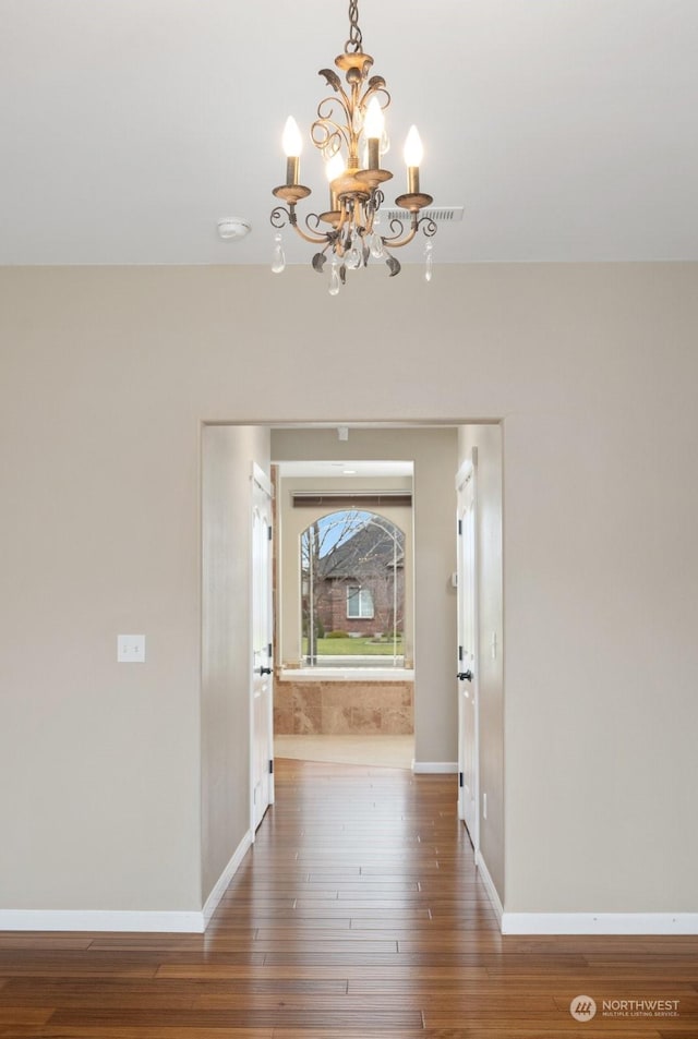 hall with dark hardwood / wood-style floors and a chandelier