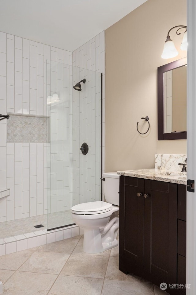 bathroom with vanity, toilet, and a tile shower