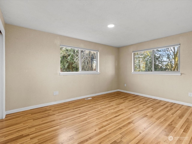 empty room with light hardwood / wood-style floors and a healthy amount of sunlight