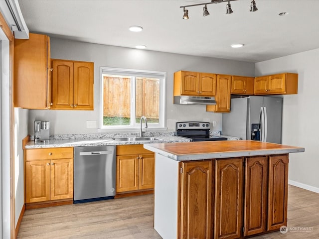 kitchen with light wood-type flooring, sink, a kitchen island, and appliances with stainless steel finishes