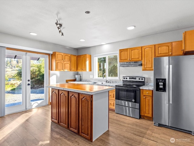 kitchen with sink, light hardwood / wood-style flooring, appliances with stainless steel finishes, a center island, and french doors
