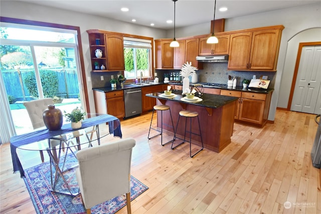 kitchen with a kitchen island, appliances with stainless steel finishes, pendant lighting, backsplash, and a kitchen breakfast bar