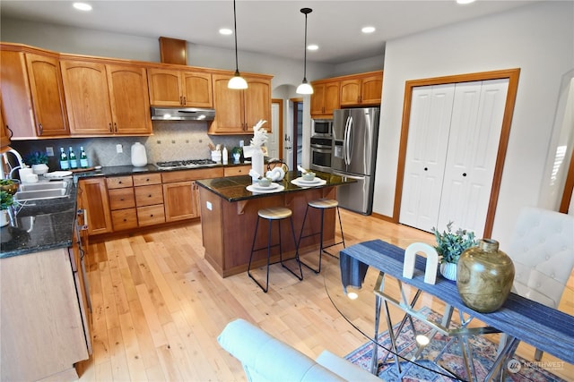 kitchen featuring a kitchen island, appliances with stainless steel finishes, sink, a kitchen bar, and hanging light fixtures