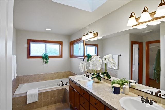 bathroom with vanity, tiled bath, and a skylight