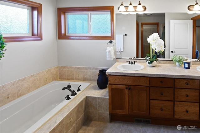 bathroom featuring vanity, tiled tub, and tile patterned flooring