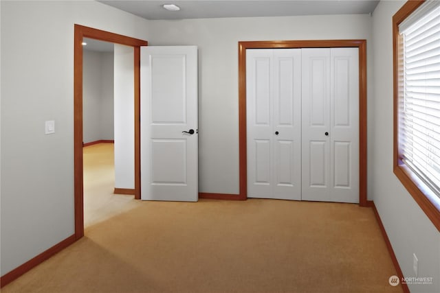 unfurnished bedroom featuring light colored carpet and a closet