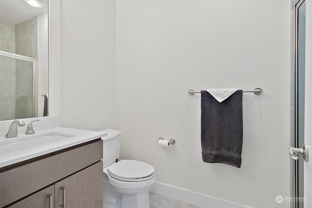 bathroom featuring a stall shower, vanity, toilet, and baseboards