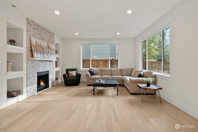 living room with recessed lighting, a fireplace, baseboards, built in features, and light wood-type flooring