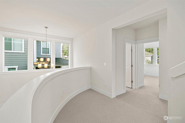 corridor featuring light carpet and baseboards