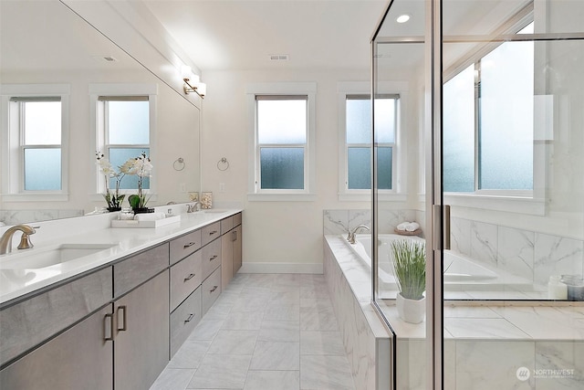 bathroom featuring double vanity, visible vents, baseboards, a bath, and a sink