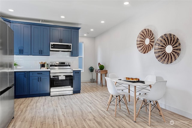 kitchen with blue cabinets, backsplash, light hardwood / wood-style floors, and appliances with stainless steel finishes