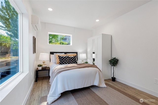 bedroom with a wall mounted air conditioner and light wood-type flooring