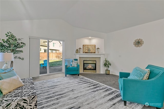 living room featuring a tiled fireplace, lofted ceiling, and carpet flooring