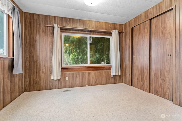 empty room with carpet and wood walls