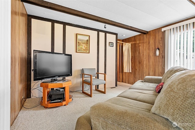 carpeted living room with beam ceiling and wood walls