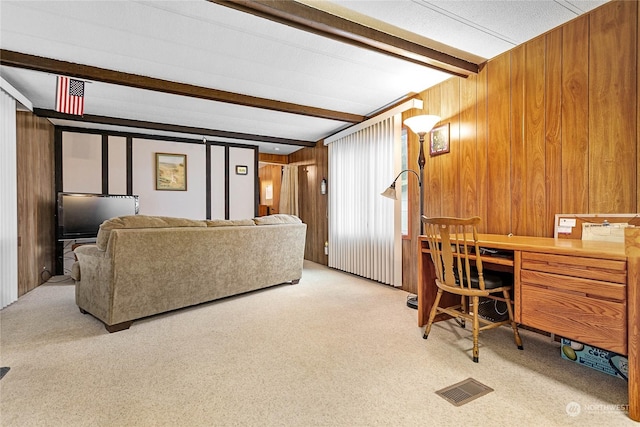 living room featuring wooden walls, light colored carpet, and beam ceiling