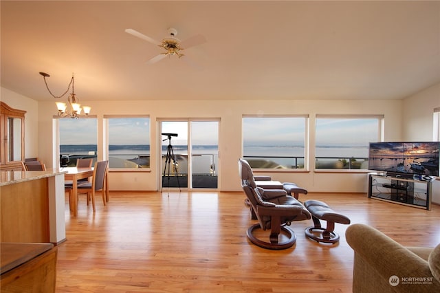 living room with ceiling fan with notable chandelier and light hardwood / wood-style flooring
