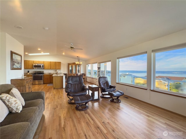 living room with light wood-type flooring, vaulted ceiling, an inviting chandelier, and a water view