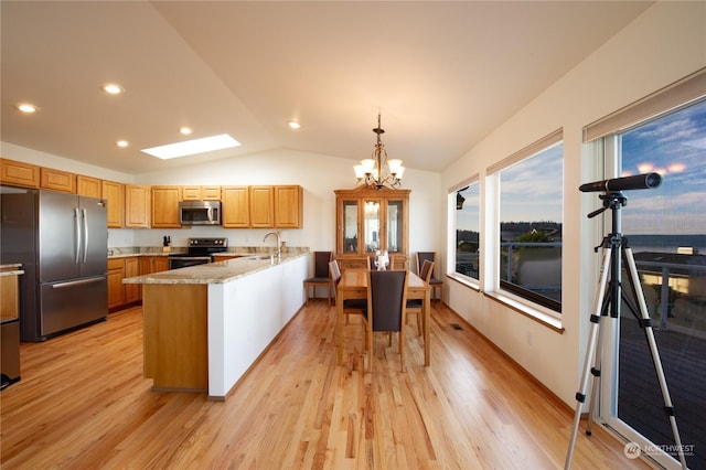 kitchen with vaulted ceiling, decorative light fixtures, sink, stainless steel appliances, and light stone countertops