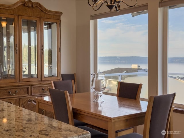 dining room with a water view, plenty of natural light, and an inviting chandelier