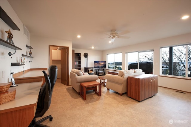 living room featuring ceiling fan and a wood stove