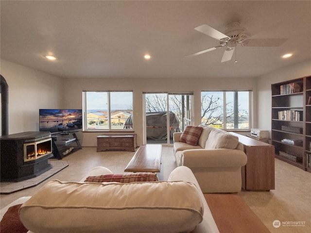 living room with a wood stove, a wealth of natural light, and ceiling fan